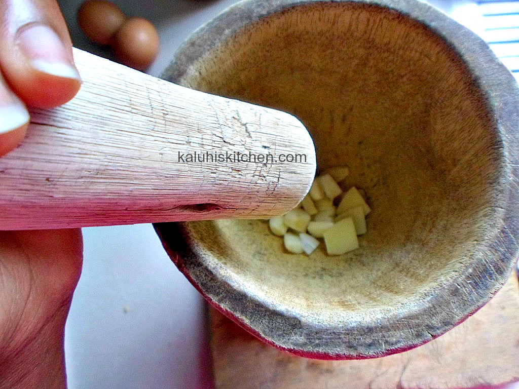 pounding garlic and ginger into a paste using a pestle and mortar; which is know as a kinu in Kenya